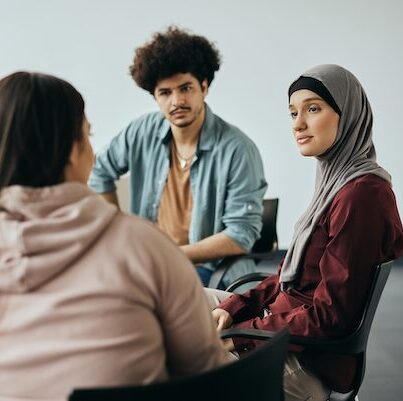 Young Muslim woman talking to group therapy members during their meeting at mental health center.