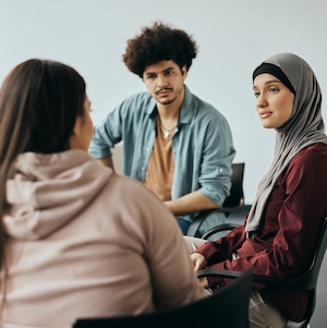 Young Muslim woman talking to group therapy members during their meeting at mental health center.